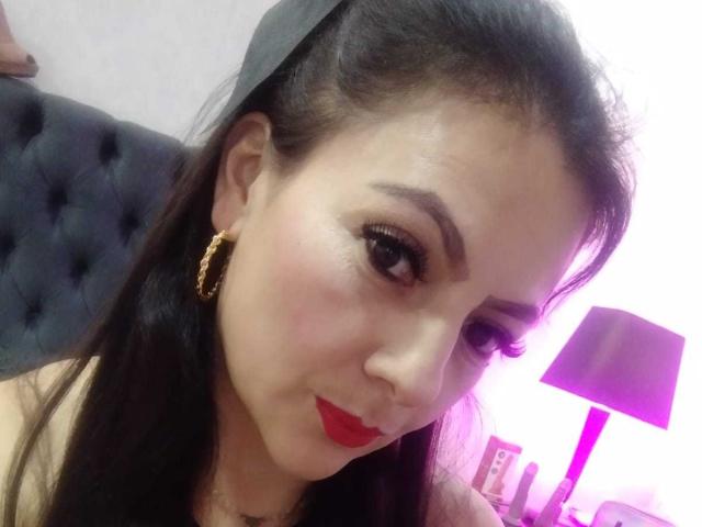 JakyKidman with long black hair, wearing a gray headband, gold hoop earrings, red lipstick, and makeup, looking at the camera, showing her cute face and sexy look.