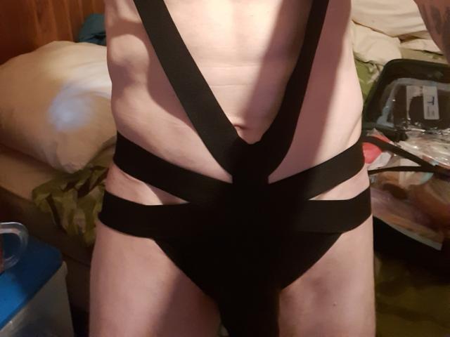 KevinLatrique wearing black strappy lingerie, exposing their pale skin and flat stomach. Their small, bare ass is covered by the black straps. KevinLatrique's navel is visible.