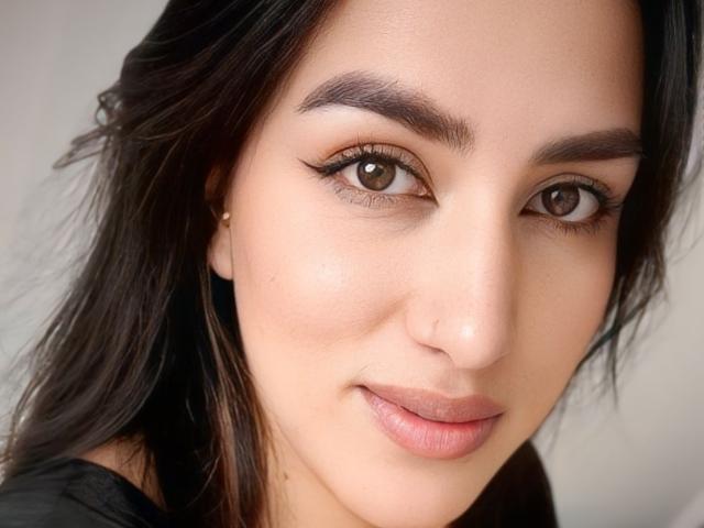 Alana Harris a les yeux marron, des sourcils foncés et un léger sourire avec du rouge à lèvres rose. Elle a la peau claire, les cheveux brun foncé et un petit nez. Son maquillage est discret..