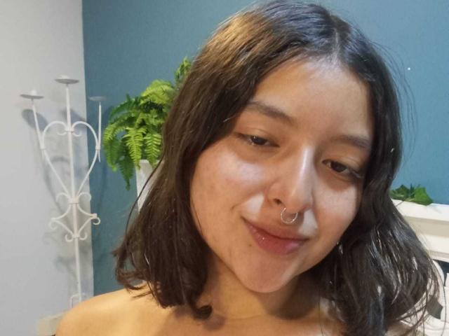 SaraiiAngel has medium-length black hair, a nose ring, and a slight smile. She's topless with a cute, fresh-faced look. Her brown eyes are gently looking at the camera.