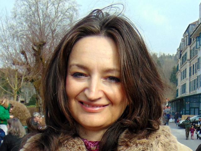 TereseHot has brown wavy hair, blue eyes, and a cute smile. She's wearing a furry coat and looking slightly to the side. Her tits are not visible.