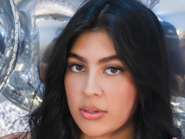 SamanthaEva69's face, with black wavy hair, brown eyes, and pink lips, is centered in the image, looking slightly to the side with a soft, neutral expression.