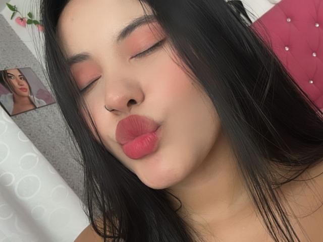 ArianaSmith69 with pouty pink lips, closed eyes, and black hair, wearing pink eyeshadow, nose piercing, and a nose ring, in a selfie. Her ass is not visible.