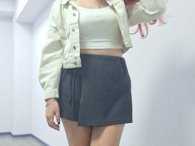 Triziya has a white crop top, black mini skirt, and beige jacket, showing her ass and a hint of her tits. She has pink hair and a bracelet.