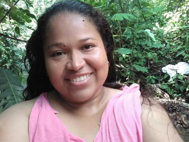 Karoline Jones ha la pelle marrone media, i capelli neri ricci ed è sorridente con le labbra rosa. Indossa una maglietta rosa senza maniche, che mostra leggermente il seno. Si trova in una foresta verde..