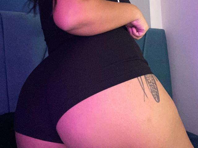 AmarantaCarey's curvy butt in black underwear, showing a tattoo on her right thigh, with her hand on her hip. Her tan skin and dark hair are visible.