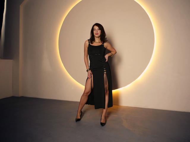 WarmMemory with dark hair, black dress, high slit, black heels, standing against glowing circle, hand on hip, confident pose, subtle smile, soft lighting, elegant, sexy.