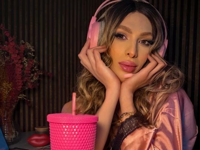 Putinna with pink headphones, hands on cheeks, pink drink with straw, and pink lips, wearing a pink satin robe, wavy blonde hair, and subtle makeup, looking sexy.