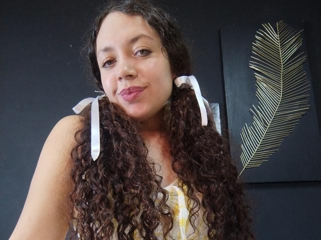 Digital art of a flat, minimalist design. Features three overlapping, abstract shapes in muted colors: pink, white, and black. Black shape has striped pattern in top right. Clean, simple.