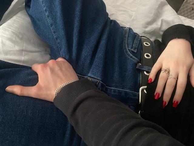 IngaFoxy with a ponytail and ear piercings, wearing a black shirt and necklace, leans in to IngaFoxy in a black leather jacket, both smiling.