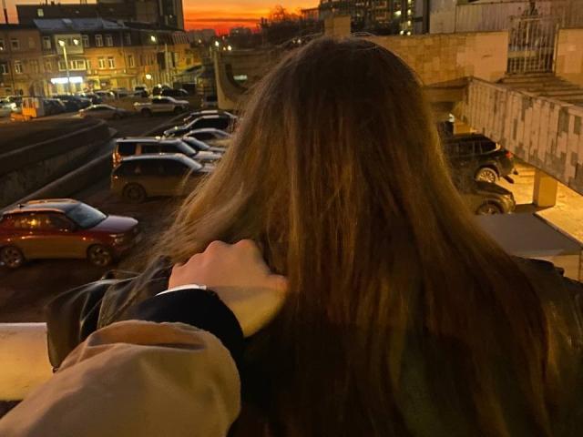 IngaFoxy mit braunen Haaren, kleinen Brüsten und einem schwarzen Top umarmt eine große IngaFoxy mit blonden Haaren, einer weißen Kapuzenjacke und grauen Hosen und macht ein Selfie in einem Raum..