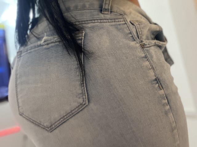 YessiJaymes' tight, gray, faded denim ass is centered, showing a prominent back pocket and slightly frayed edges. Her black, straight hair is partially visible.