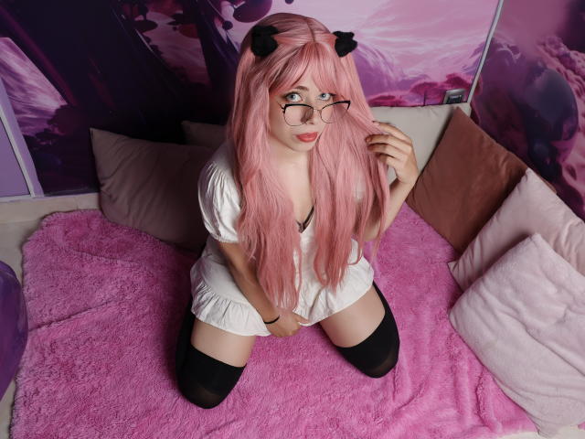 KylieLong mit rosa Haaren, Katzenohren, Brille, weißem Kleid, schwarzen Oberschenkelstrümpfen, kniet auf einer rosa Decke, Hände auf dem Schoß, süß, sexy, blasse Haut, rosa und lila Hintergrund..