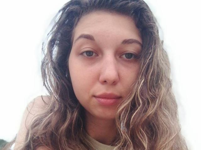 Sapfira a les cheveux ondulés, d'un blond sale, des yeux marron clair et une expression neutre. On peut voir son petit nez et ses lèvres légèrement entrouvertes. Elle porte une chemise de couleur claire..