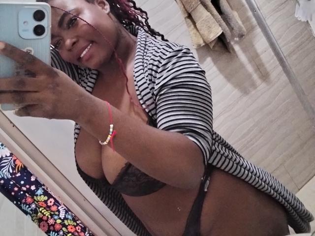 KarlaFlorez taking a mirror selfie, wearing a striped robe, black lace bra, and black thong, showing her tits and ass, with a red bracelet and curly red hair.