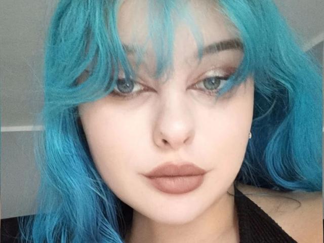 LunaGeil, met felblond haar, bleke huid en volle, sensuele lippen, draagt subtiele eyeliner en mascara, heeft een kleine, puntige neus en een serieuze, bijna verleidelijke uitdrukking..