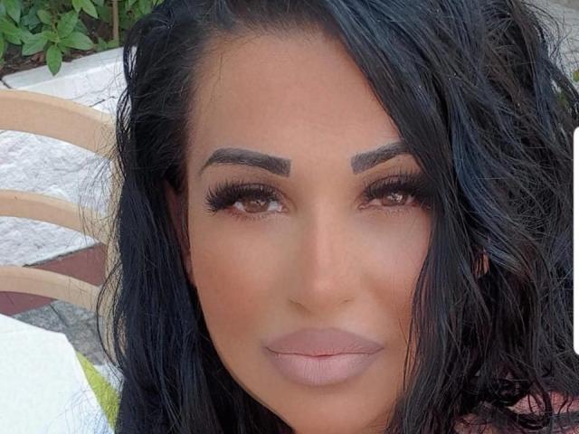 Monasquirt4u2 has dark brown eyes, thick black eyebrows, long black eyelashes, and a slightly parted pinkish-brown mouth. Her black hair is wavy and falls to the sides.