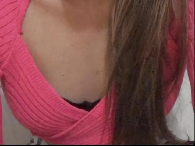 Sol69's tits are partially covered by a pink ribbed sweater with a black bra underneath. Sol69's brown hair is falling to the right.