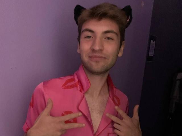 JosephBest with cat ears, pink shirt with red lipstick patterns, hands on chest, smiling, brown hair, slight beard, light skin, casual, sexy, cute, slightly flirty.