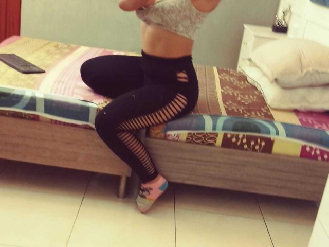 BrianaCleython sits on a bed, wearing a gray lace bra and black ripped leggings, exposing her legs, with colorful socks, showing her ass and flat stomach.