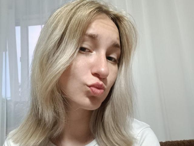 Blonde BeautyGinger with puffy lips, white shirt, and slightly messy hair, making a silly face in a selfie.