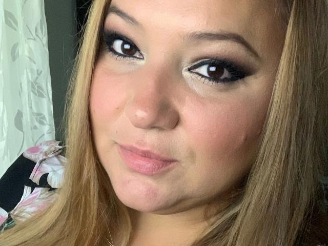 LaVa24-hot has light brown eyes, blonde hair, and pink lips. She's making a pouty face with slightly flushed cheeks and subtle black eyeliner. Her nose is small and cute.