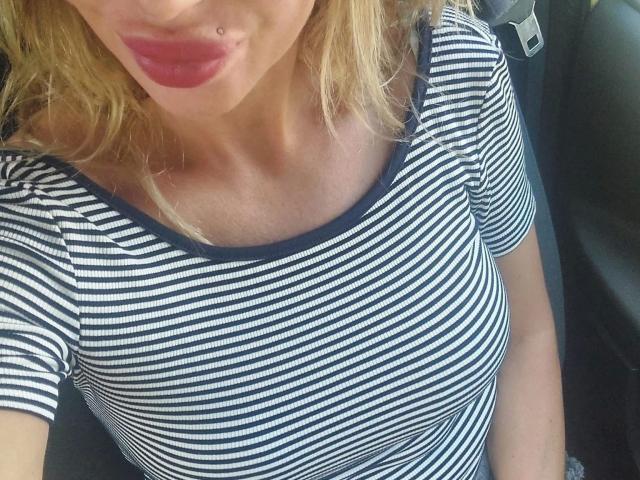 LauraRubin-hot in a striped navy and white shirt, showing her small tits and a lip piercing with red lipstick, sitting in a car.
