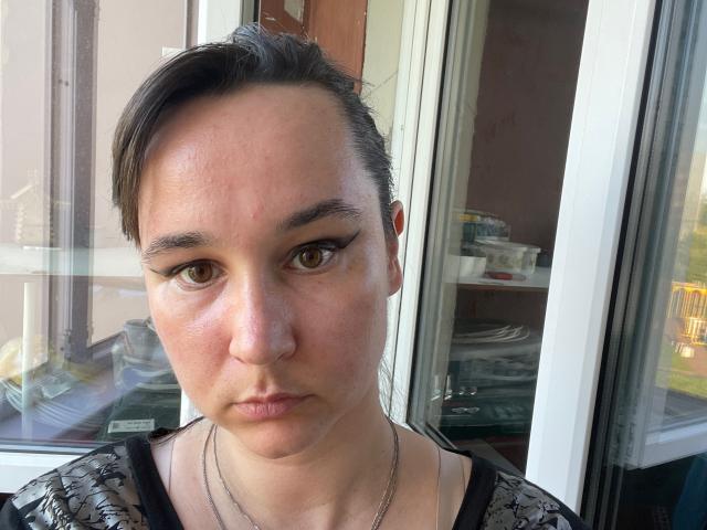 SaliBerry has a serious face, brown eyes, and short dark hair with a small part. She's wearing a black lace top and a silver necklace. Her ass is not visible.