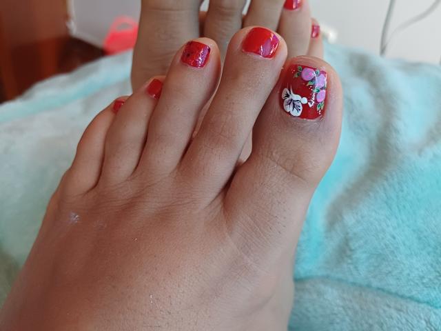 Apasion's foot with red nail polish and a floral design on the big toe, showing slightly dirty toes against a blue towel.