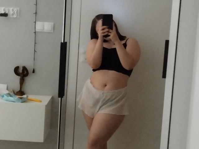 AbbyMaus-hot with small tits, black crop top, white shorts, holding phone, covering face, standing in mirror, mirror reflection, medium build, brown hair, in bedroom, selfie.