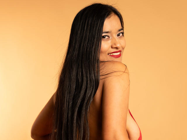 ValeriaHotVelez with long black hair, smiling, red lipstick, looking back, showing her back and red bra, tan skin, sexy, attractive, smiling, looking over shoulder.