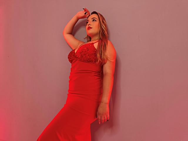 ZoeTobon69, red dress, sparkly top, long blonde hair, red lips, arm raised, hand on wall, red light, sexy, curvy, hourglass figure, elegant, standing, looking up.
