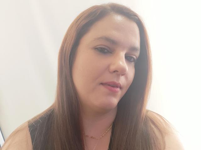 AmeliaWilson has straight brown hair, light skin, and a slight smirk. She's wearing a black pinstripe shirt with a gold necklace. Her eyes are half-open.