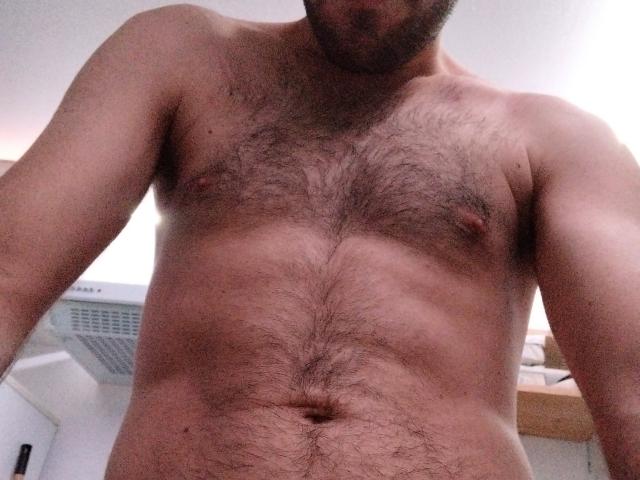 TitiHotMan is a hairy, shirtless guy with a hairy chest, hairy belly, and visible nipples. His face is partially out of frame, showing a beard.