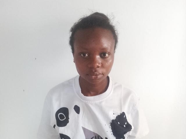 ClaraXymena, dark-skinned with curly hair, wearing a white t-shirt with black abstract patterns, has a serious, almost pouty expression, standing against a plain white background.