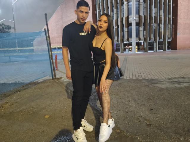 KylieAndJustin with short black hair and Justin with a black shirt and white sneakers, standing next to KylieAndJustin with long black hair, dark lipstick, black top, fishnets, and white sneakers.