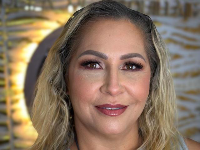 MajaReal has blonde wavy hair, brown eyes, and a cute smile with red lipstick. Her makeup is subtle with dark eyeliner and mascara. She's looking directly at the camera.
