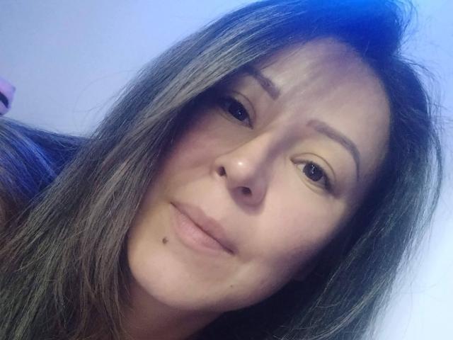 Contelaya's face, with brown eyes, subtle makeup, and long brown hair, showing a small beauty mark below her right nostril. She's looking at the camera with a slight smile.