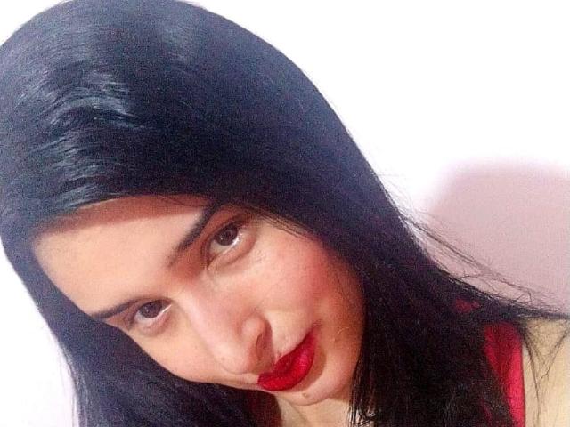 AngelSofiaSecond with long black hair, brown eyes, red lipstick, and a slight smile, looking down at the camera. She has a cute, sexy, and attractive face.