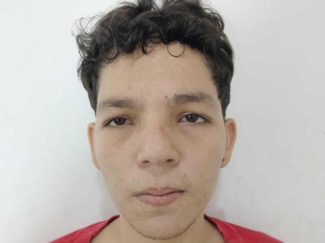 DeivisSexLov has curly dark hair, light brown skin, brown eyes, and a red shirt. His face is slightly freckled with a neutral expression.