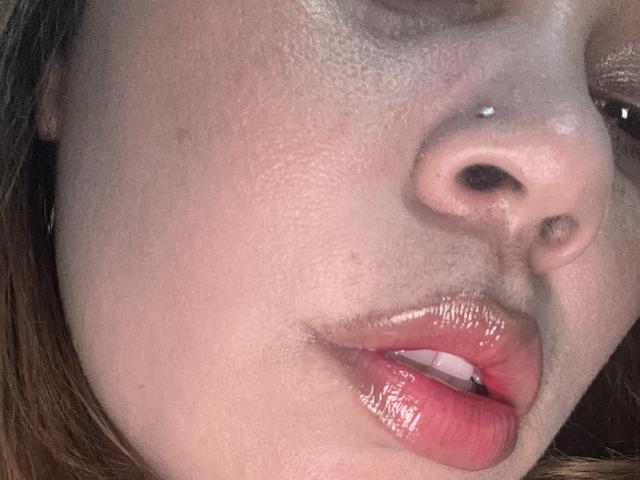 SophiaQueens' face, showing a nose piercing, slightly parted glossy red lips, and a small upper lip, with visible skin texture and light brown hair on the left.