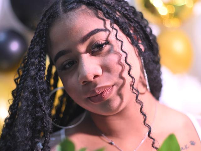 SofiFoxy69 has curly black hair, pouty lips, and a light brown skin tone. She's wearing white earrings, and her shadowy face is slightly angled to the camera.