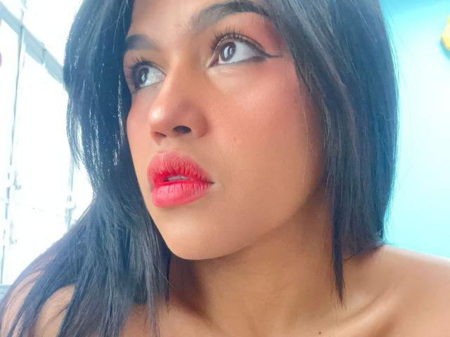 NairobiSwan's face, dark black hair, red lipstick, slightly open mouth, brown eyes looking up, smooth tan skin, small zit on right cheek, no clothes visible.
