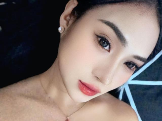 HeartOfAsysa has smooth, fair skin, dark eyebrows, blue eyes, red lipstick, and black hair, wearing pearl earrings, with a subtle necklace, looking directly at the camera.