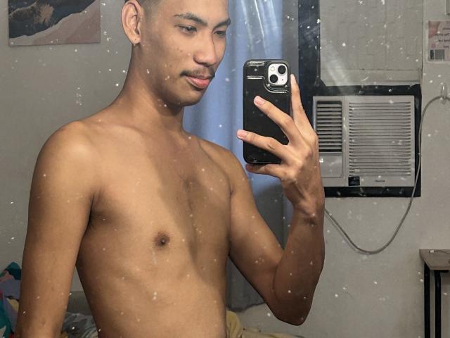 Shirtless HiddenDesireAru with light brown skin, short dark hair, and a mustache, holding a phone, taking a mirror selfie, showing a toned, slim upper body.