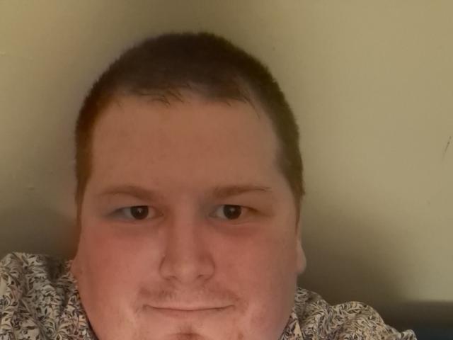 LoveDoux has a chubby face with short brown hair, a small mustache, and is wearing a patterned shirt, looking directly at the camera with a slight smile.