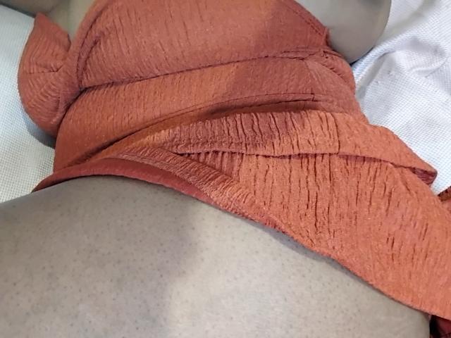 WendyStacey's orange dress is pulled up, revealing her chubby, freckled pussy and part of her ass. The dress has a textured, ribbed pattern.