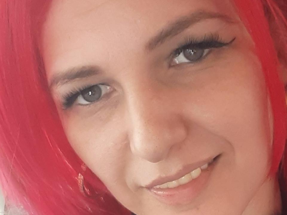 EvaDesireOne with bright red hair, blue eyes, and long eyelashes, smiling at the camera. She has light skin, subtle freckles, and a cute, slightly mischievous look.