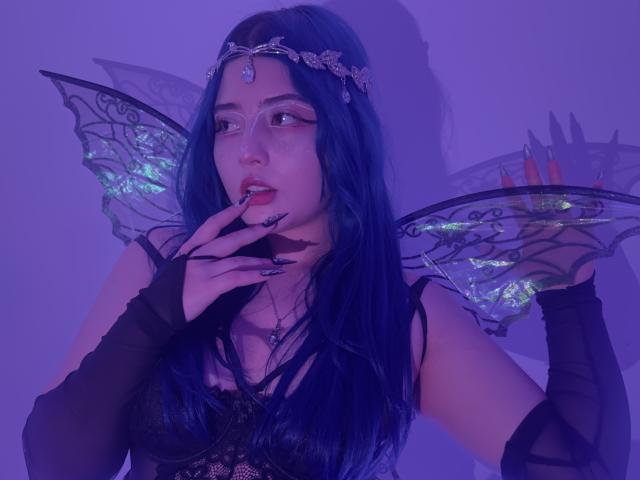 AmeliaXWalker with blue hair, fairy wings, and black lace top, finger in mouth, wearing a headpiece, black gloves, purple lighting, and neon green wing details, looking seductive.