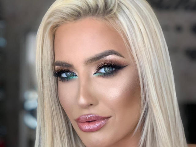 BlancheSummer has blonde hair, blue-green eyes, and glossy pink lips. Her makeup includes dark eyeliner and smoky eyeshadow. She has a smooth, tan complexion.